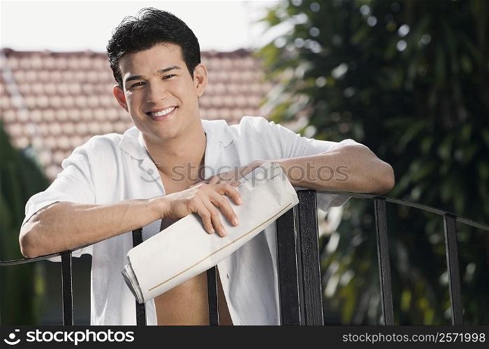 Young man holding a newspaper and smiling
