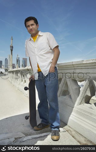 Young man holding a skateboard and looking away