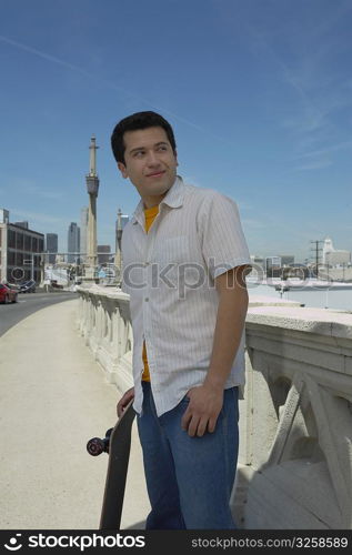 Young man holding a skateboard and looking away