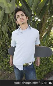 Young man holding a skateboard behind his back