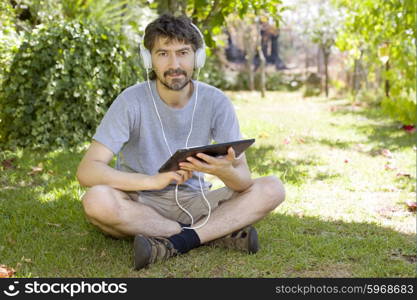 young man holding a tablet with headphones, outdoor