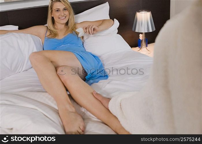 Young man holding a young woman&acute;s leg on the bed