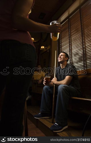 Young man holding billiards cue while hanging out at pub.