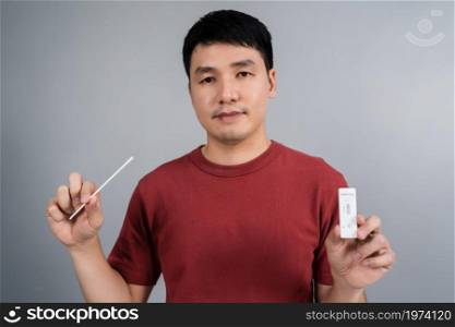 young man holding Coronavirus(Covid-19) positive test result with SARS-CoV-2 Antigen Rapid Test kits for Self testing at home