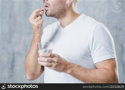 young man holding glass water taking medicine