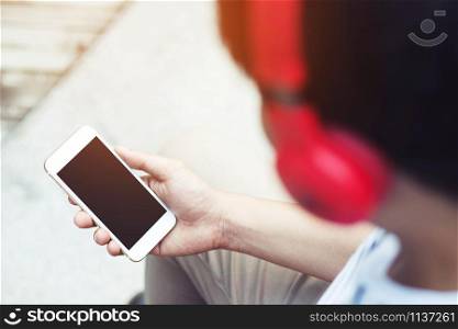young man holding hand smart phone using earphone to listening to music with isolated copy space empty screen for changes song and tracks on mobile. headphone Enjoying the rhythm. technology concept