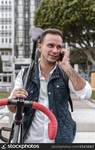 young man holding his bike talking phone
