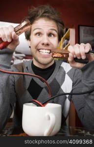 Young man holding jumper cables coming out of coffee mug