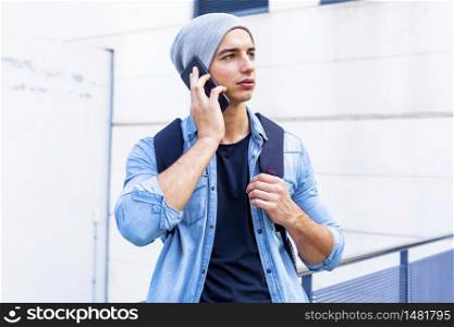 Young man holding mobile phone, using smartphone, making a call, talking on the phone