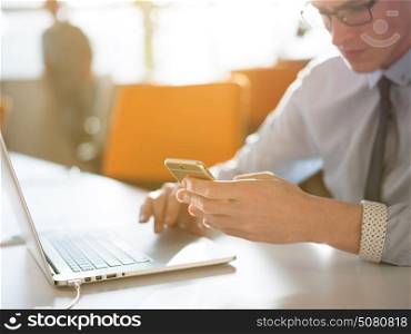 Young man holding on his smartphone in the office close up