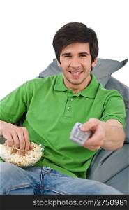Young man holding remote control watch television and eat popcorn on white background