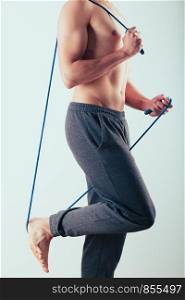Young man holding skipping rope, doing exercises at home. Portrait orientation