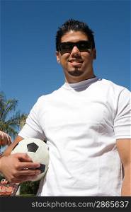 Young man holding soccer ball outdoors portrait