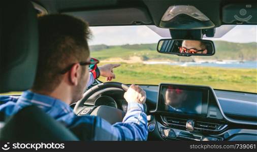 Young man holding steering wheel and pointing while driving the car. Young man holding steering and pointing driving