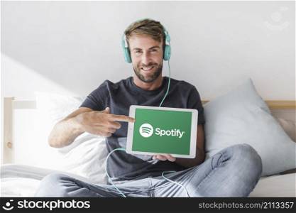 young man holding tablet with spotify app