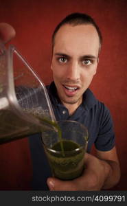 Young man holding unappetizing blended health shake