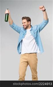 Young Man holding wearing jeans shirt Bottle of beer standing over Grey Background.. Young Man holding wearing jeans shirt Bottle of beer standing over Grey Background