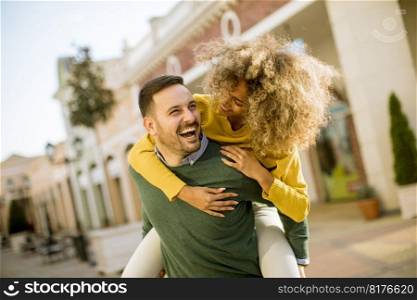 Young man holds a young woman on his back and entertaining themselvs outdoor