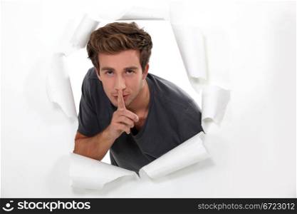 young man holds finger before his mouth