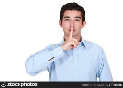 young man holds finger before lips