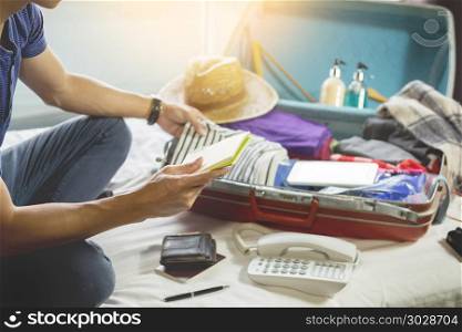 Young man hurring up to meeting and talking by phone and taking notes packing for Preparation travel suitcase at home.. Young man hurring up to meeting and talking by phone and taking