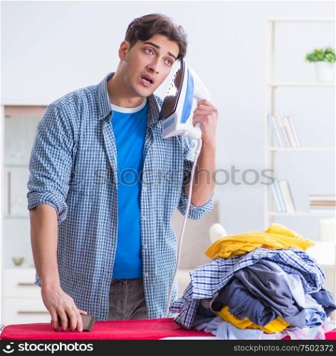 Young man husband doing clothing ironing at home. The young man husband doing clothing ironing at home