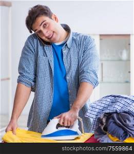 Young man husband doing clothing ironing at home. The young man husband doing clothing ironing at home