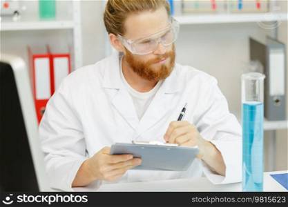 young man in a lab coat making notes