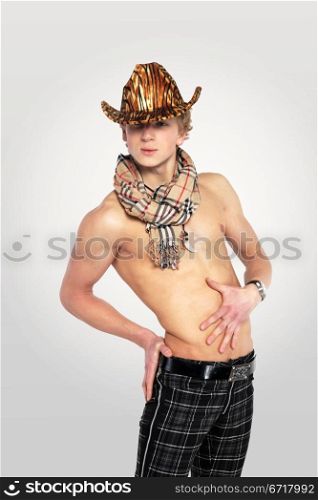 young man in a leopard print hat on tne white grey background, with a naked torso