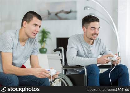 young man in a wheel playing video games with friend