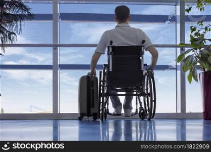 Young man in a wheelchair with luggage at the airport closeup