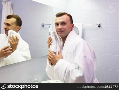 young man in bathroom wearing white bathrobe