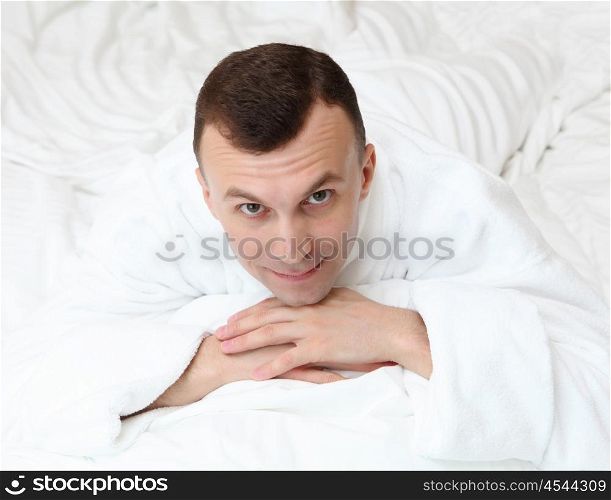 young man in bed in white bathrobe