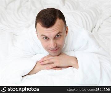 young man in bed in white bathrobe
