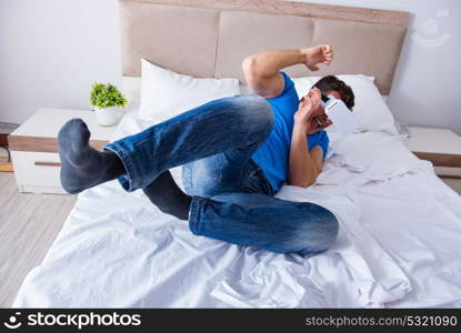 Young man in bed wearing a vr virtual reality head set