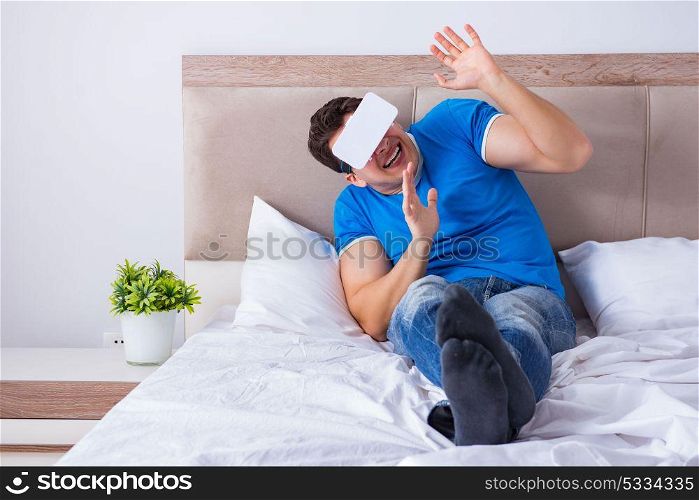 Young man in bed wearing a vr virtual reality head set