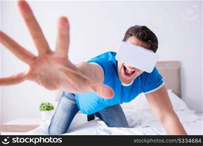 Young man in bed wearing a vr virtual reality head set
