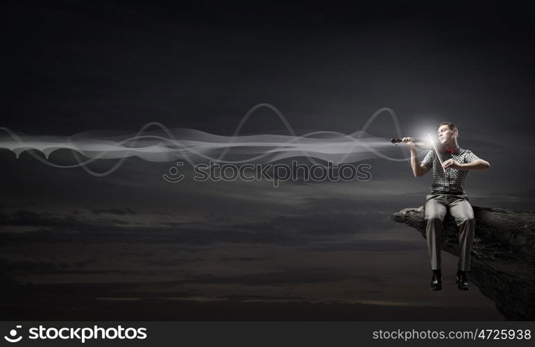 Young man in bow tie playing violin. Male violinist