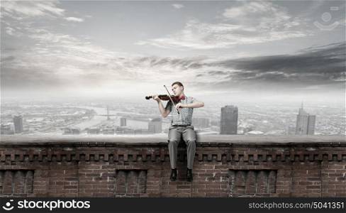 Young man in bow tie playing violin. Male violinist