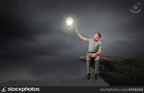 Young man in bow tie sitting with book in hands. Light of education