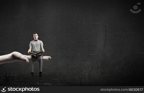 Young man in bow tie sitting with book in hands. Light of education