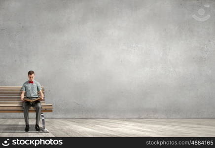 Young man in bow tie sitting with book in hands. Light of education