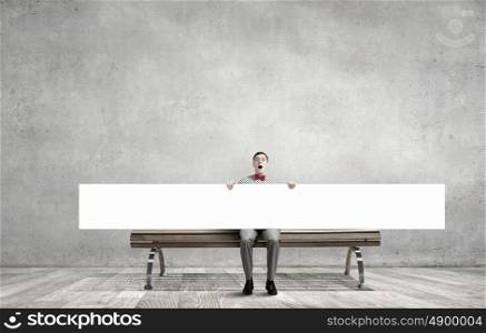 Young man in bow tie sitting with white blank banner . Place for your text