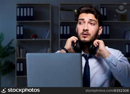 Young man in call center concept working late overtime. Young man in call center concept working late overtime in office