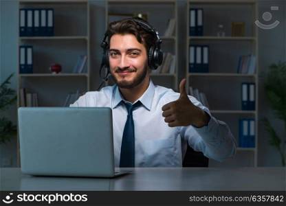 Young man in call center concept working late overtime. Young man in call center concept working late overtime in office