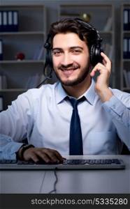 Young man in call center concept working late overtime in office . Young man in call center concept working late overtime in office