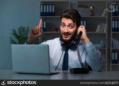 Young man in call center concept working late overtime in office . Young man in call center concept working late overtime in office