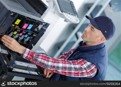 young man in cap working on offset printing machine