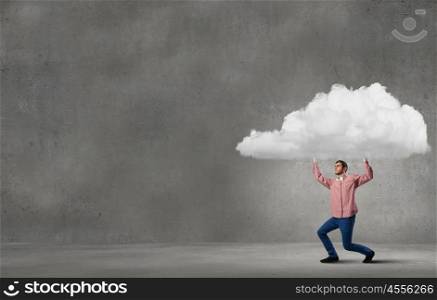 Young man in casual carrying cloud above head. Man lifting cloud