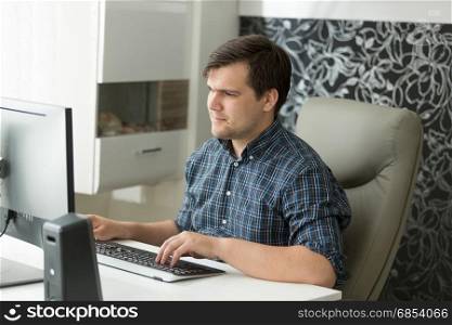 Young man in casual clothes working at office